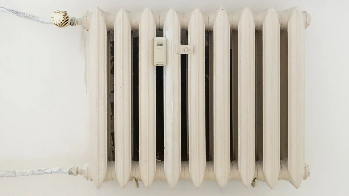 Balts sekciju radiators pie gaišas telpas sienas