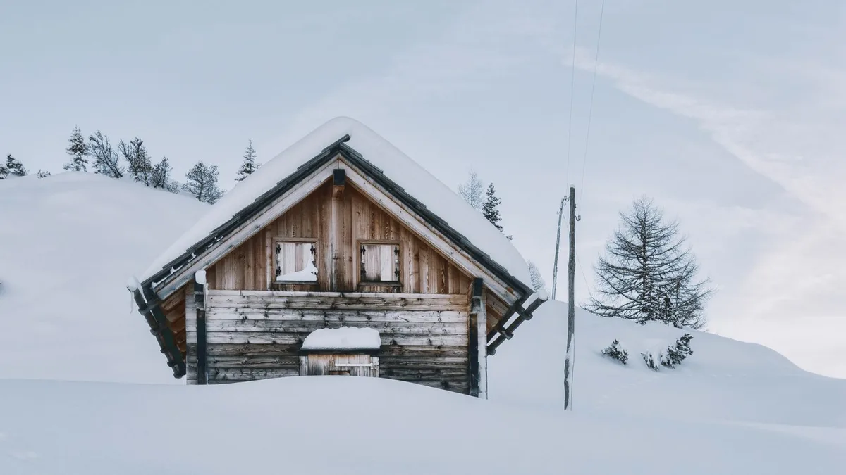 Koka māja sniegotā ainavā